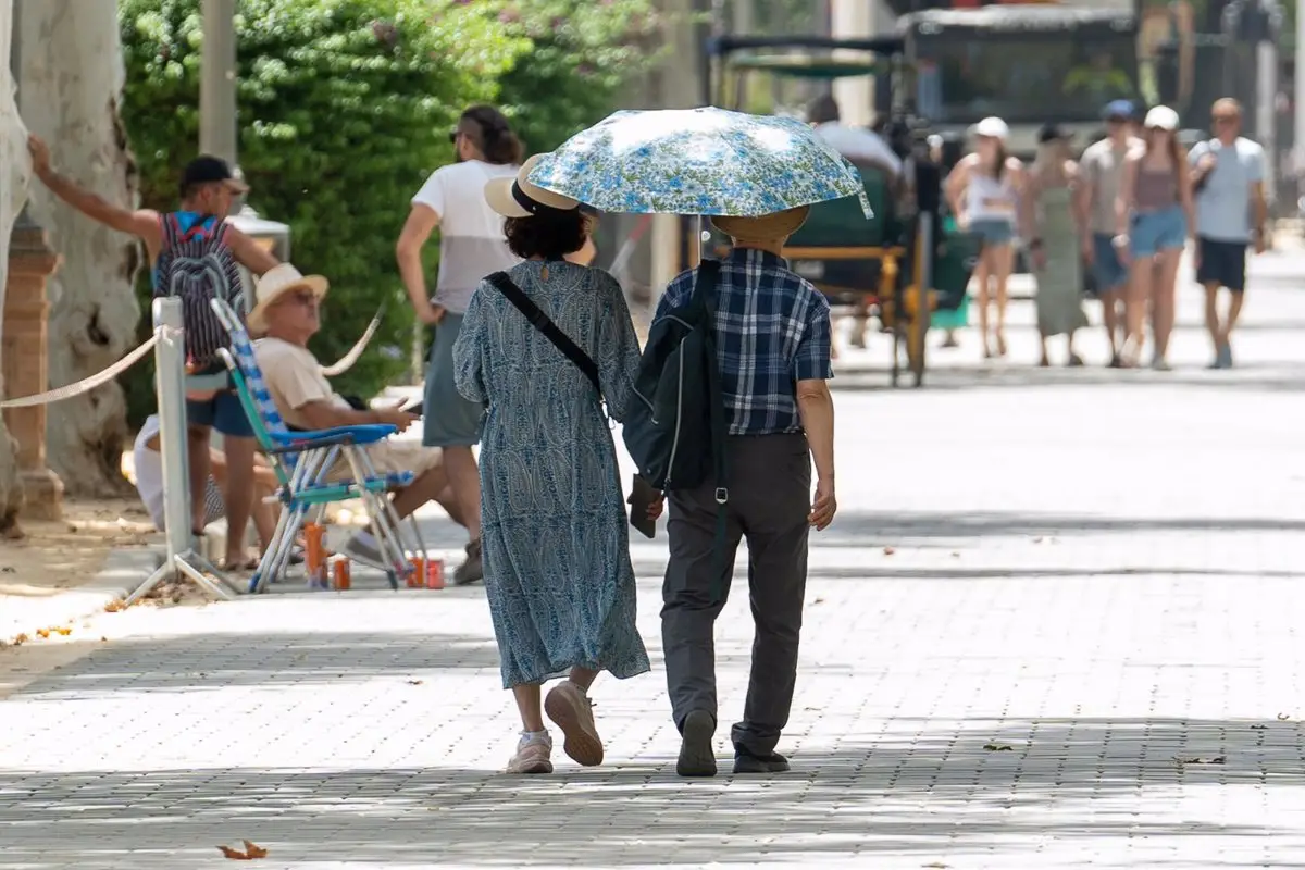 Unos turistas pasean por la ciudad resguardados del calor por un paraguas en Sevilla / Foto: Archivo - EP