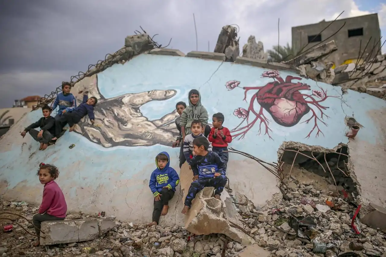 Industria militar e impacto ambiental. Unos niños palestinos desplazados internamente juegan junto a un mural pintado sobre los escombros de una casa en Deir Al Balah, en la Franja de Gaza / Foto: SINC