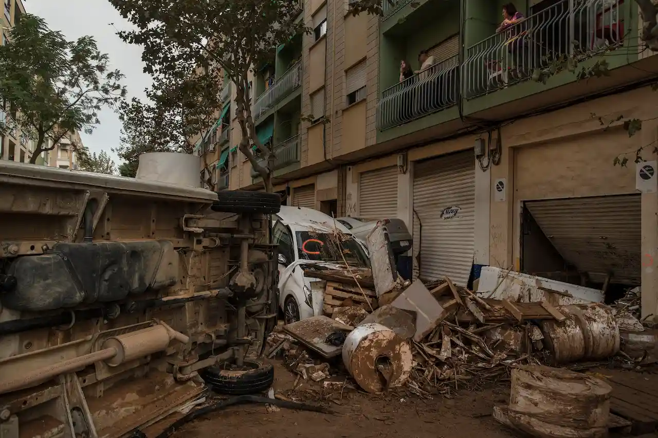 Unos vecinos del barrio de Orba en Alfafar observan desde su balcón el caos de coches y escombros arrastrados por la fuerza del agua / Foto: Alfons Rodríguez