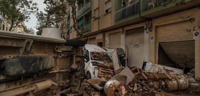 Unos vecinos del barrio de Orba en Alfafar observan desde su balcón el caos de coches y escombros arrastrados por la fuerza del agua / Foto: Alfons Rodríguez